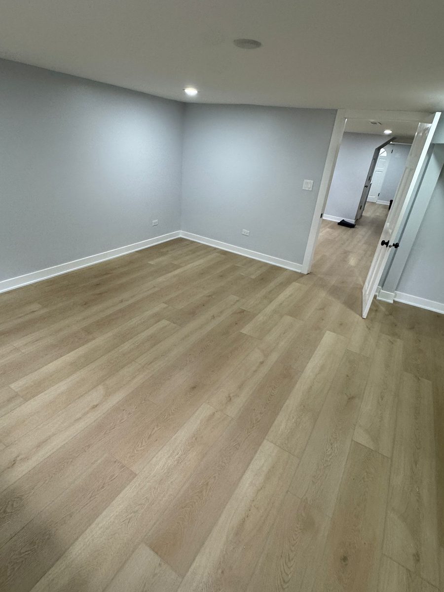The same lower level from the doorway, showing the plank carried through from room to hallway without a break.
